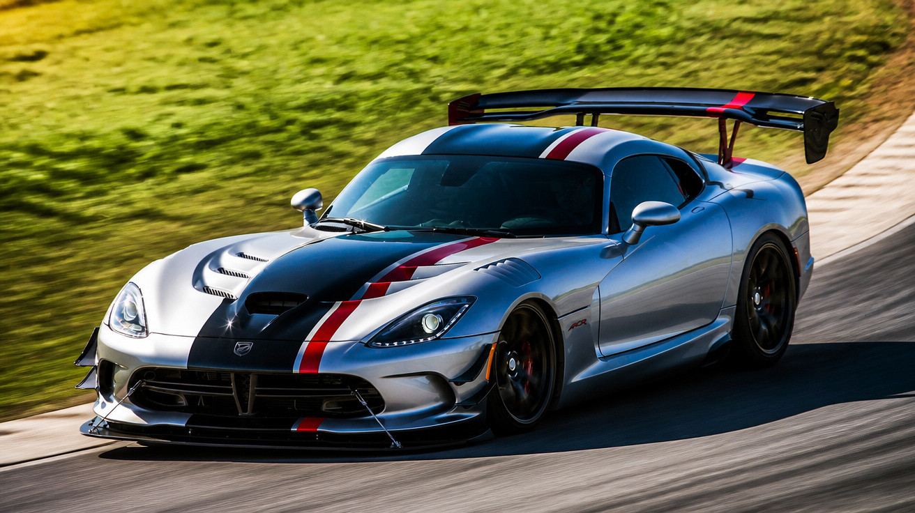 Carro esportivo prata com faixa preta e vermelha em curva de pista de corrida com grama ao fundo.