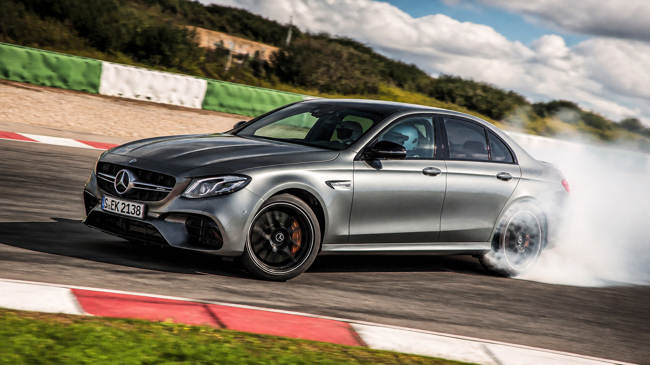 Carro esportivo Mercedes-Benz cinza fazendo derrapagem em pista de corrida com fumaça nos pneus.